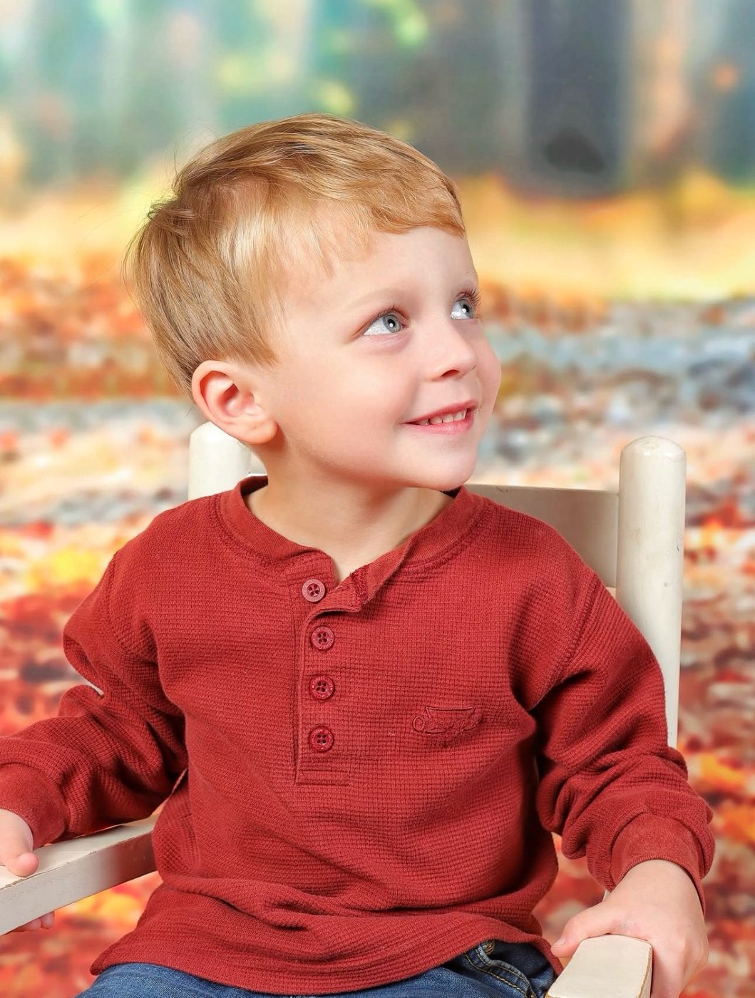 Young boy smiling on the autumn woodland portrait backdrop
